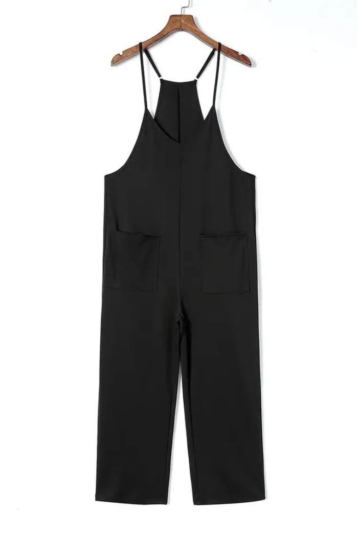 A black, sleeveless jumpsuit with a V-neck and wide legs. It has two large pockets on the front. The jumpsuit is hanging on a hanger against a white background.