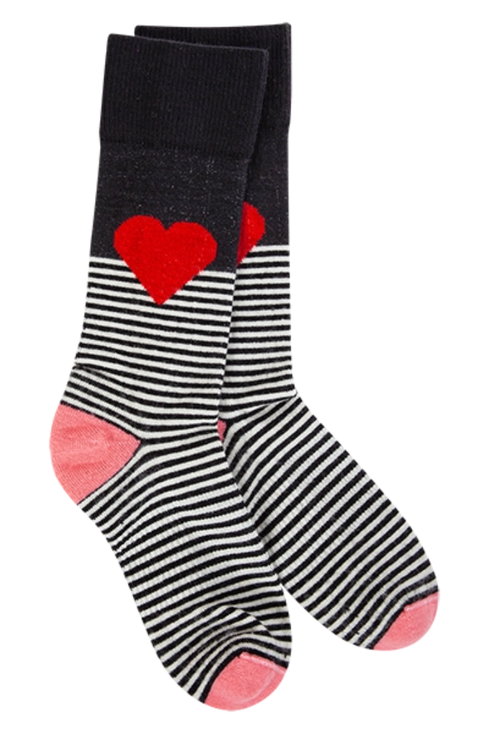A pair of crew-length socks featuring a black and white horizontal stripe pattern on the foot and ankle, transitioning to a solid black cuff, and adorned with a prominent red heart design on the side of the ankle and foot area of each sock. The heel and toe sections are a soft pink color.