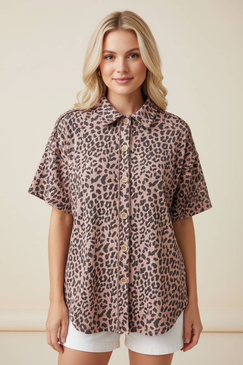 A woman with long blonde hair wears the Leopard Button Blouse in a pink and black leopard print, styled with white shorts, standing against a neutral background.