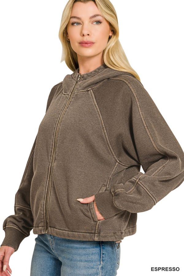 Woman wearing the Pigment Dye Zip Up Hoodie in brown with visible seams and blue jeans, standing with one hand in her pocket. Relaxed fit for comfort. “ESPRESSO” appears in the lower right corner.