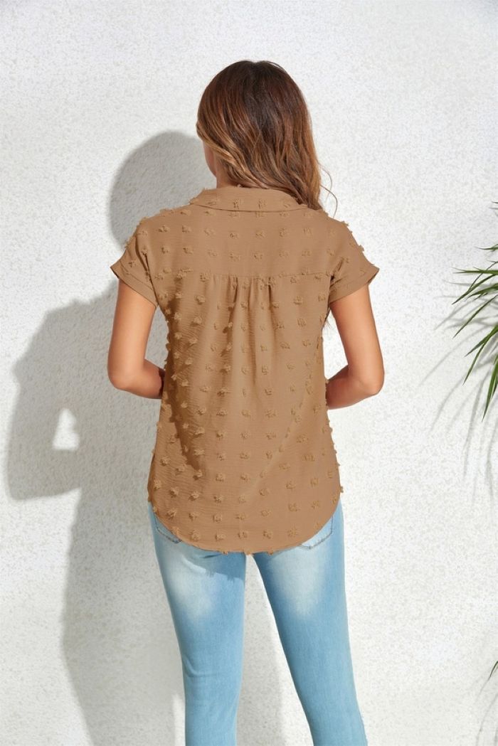 A woman with long hair faces a white textured wall wearing a Textured Button Blouse in light brown and light blue jeans. A green plant is partially visible on the right.