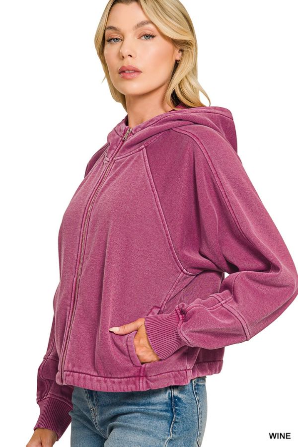 Woman wearing a wine-colored Pigment Dye Zip Up Hoodie with a relaxed fit and adjustable hem, standing sideways with one hand in her pocket, paired with light blue jeans against a white background.