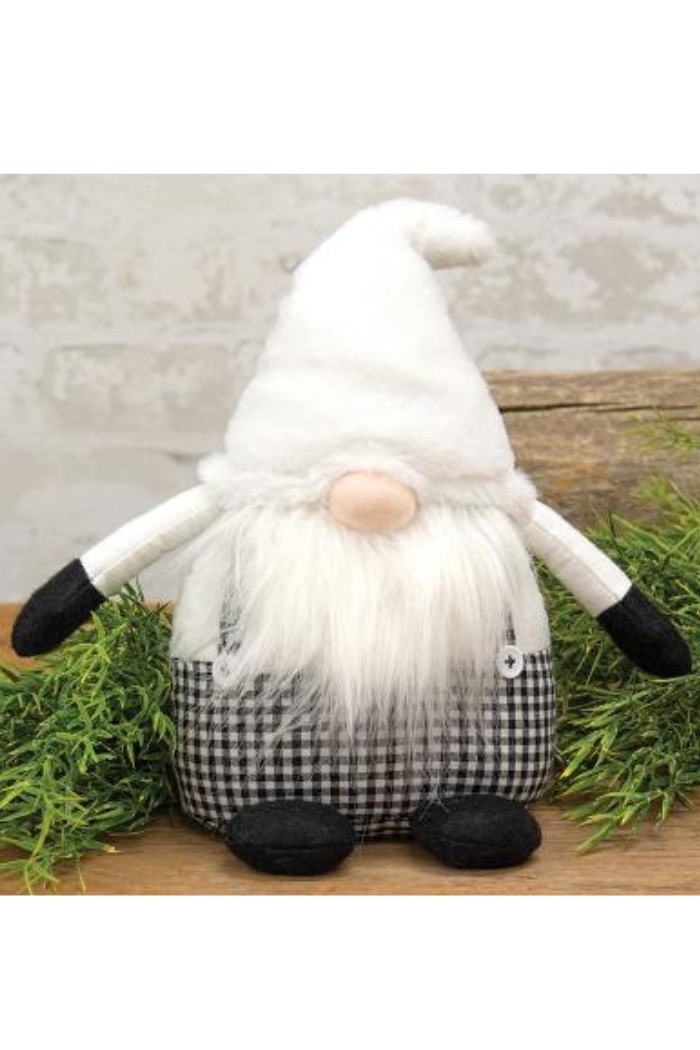 Gnome figurine with a checkered outfit sitting on a wooden surface with greenery.