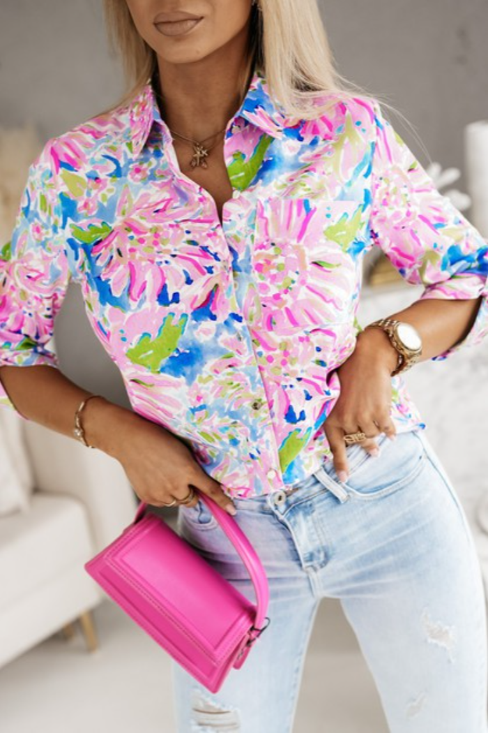 Person wearing a colorful floral shirt and holding a pink handbag indoors.