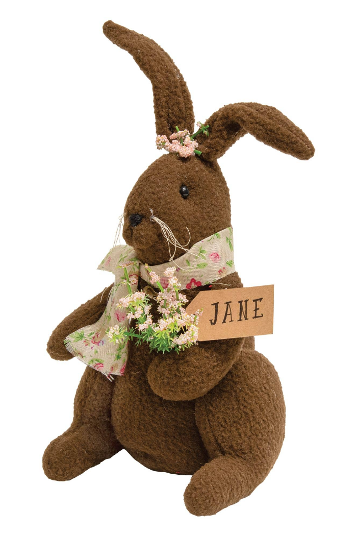 Brown stuffed bunny with floral decorations and a 'JANE' sign on a white background