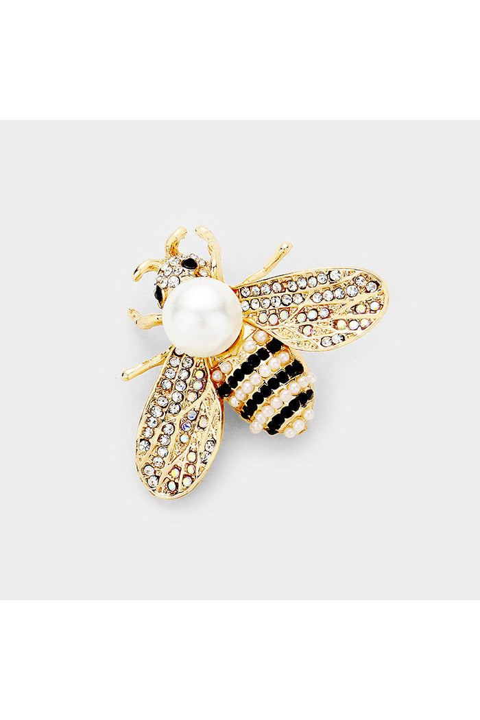 bee-shaped brooch, primarily gold in color, with a large, round, white pearl forming the body. The wings are detailed with small, clear crystals, while the abdomen features black and white enamel stripes.