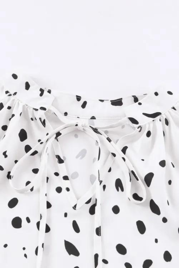 White top with black polka dot pattern on a white background