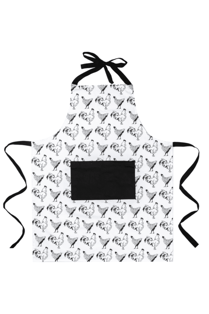 White apron with a repeating pattern of black and white rooster and hen outlines. The apron has a black pocket sewn onto the front and black ties for the neck and waist.