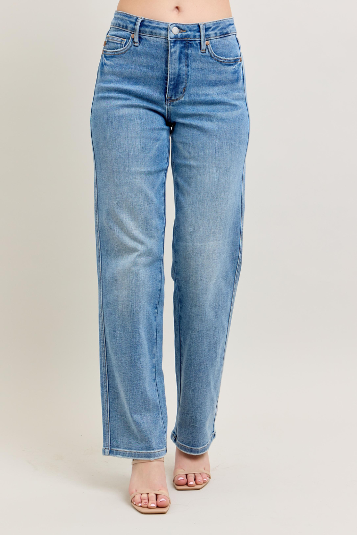 Blue jeans worn by a person on a beige background.
