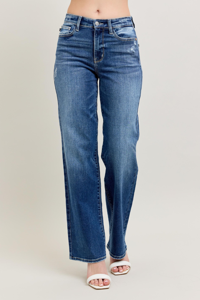 A pair of dark wash, high-waisted, 90's straight-leg jeans, likely by Judy Blue, shown on a model against a plain background. The jeans feature a classic five-pocket style and have a relaxed, straight fit through the leg.