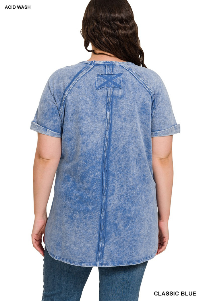 A rear view of a person wearing a classic blue, acid-wash, short-sleeved pullover with cuffed sleeves and a double back seam.

