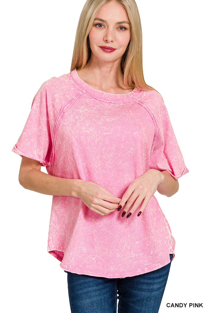 A woman with long blonde hair wearing a relaxed-fit, short-sleeved, pink mineral wash t-shirt with visible seams and a rounded hem. The text "CANDY PINK" is visible in the bottom right corner.