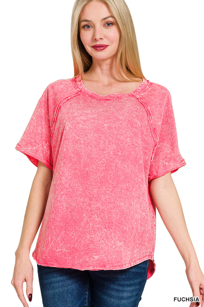 A woman models a fuchsia-colored, short-sleeved, crewneck top with a mineral or acid wash finish and visible seam details, possibly made of French terry fabric. 

