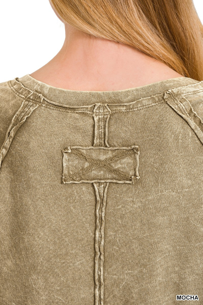 A close-up view of the back of a light brown or mocha-colored garment, likely a shirt or sweatshirt, showing a distressed or vintage-washed texture. A prominent stitched detail resembling a rectangular patch with an "X" pattern is centered on the upper back, connected by a vertical seam extending downwards. The word "MOCHA" is visible in white text in the bottom right corner of the image.