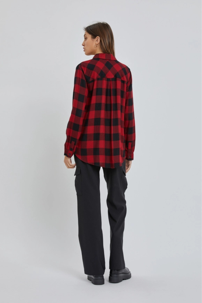 A person standing with their back to the viewer, wearing a red and black plaid long-sleeved shirt and loose-fitting black cargo pants with platform black shoes.