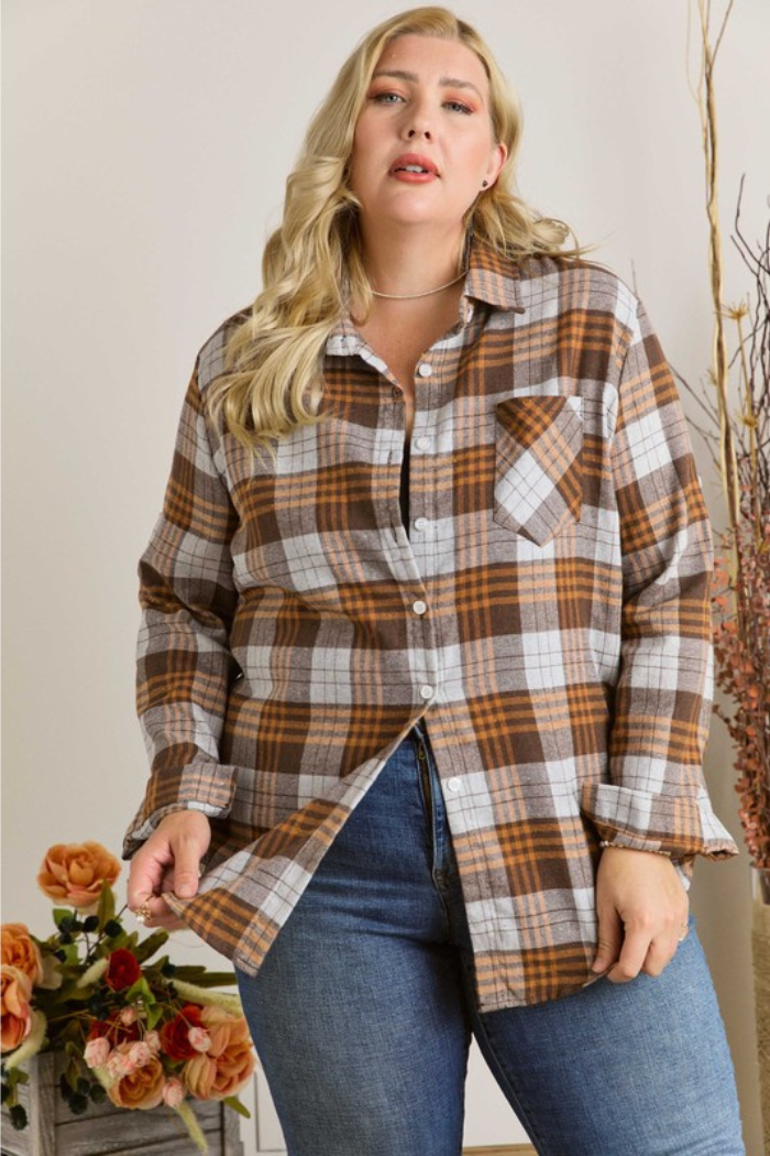 The image shows a woman wearing a plus-size brown, brown/grey plaid flannel shirt. This style is commonly referred to as a "plaid shacket" (a shirt-jacket) due to its casual, oversized fit. 