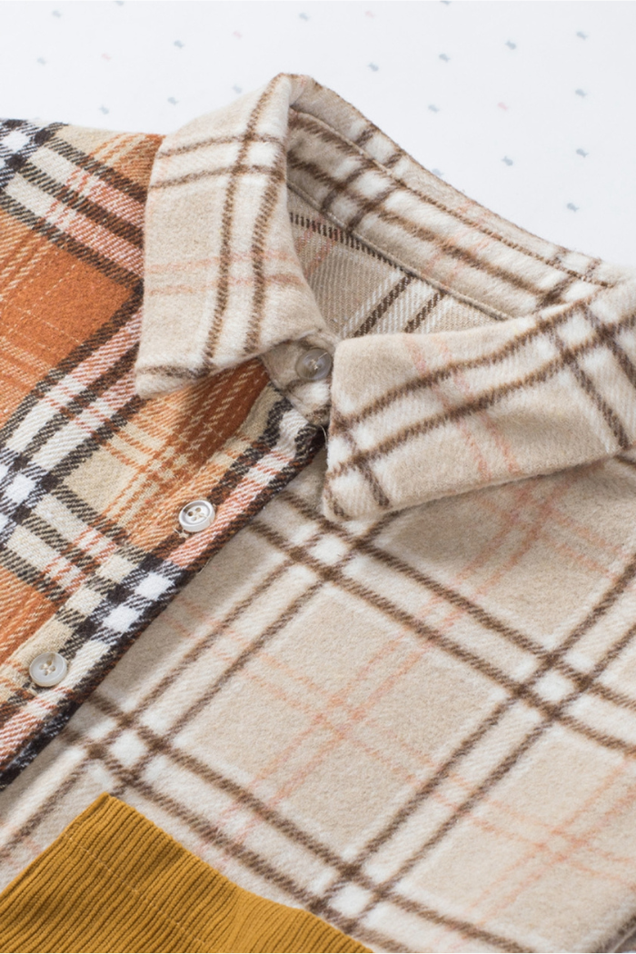 A close-up view of a plaid color-block patchwork shirt jacket, featuring different plaid patterns in shades of beige, brown, and orange, with a visible collar, button placket, and a mustard yellow corduroy patch at the bottom left.