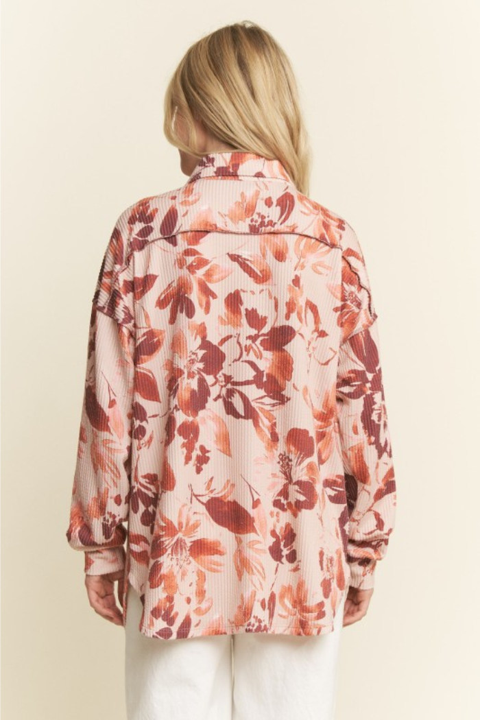 Back view of a woman with blonde hair wearing a Taupe Floral Ribbed Knit Button-Down shirt featuring a floral print in shades of pink, taupe, and orange.