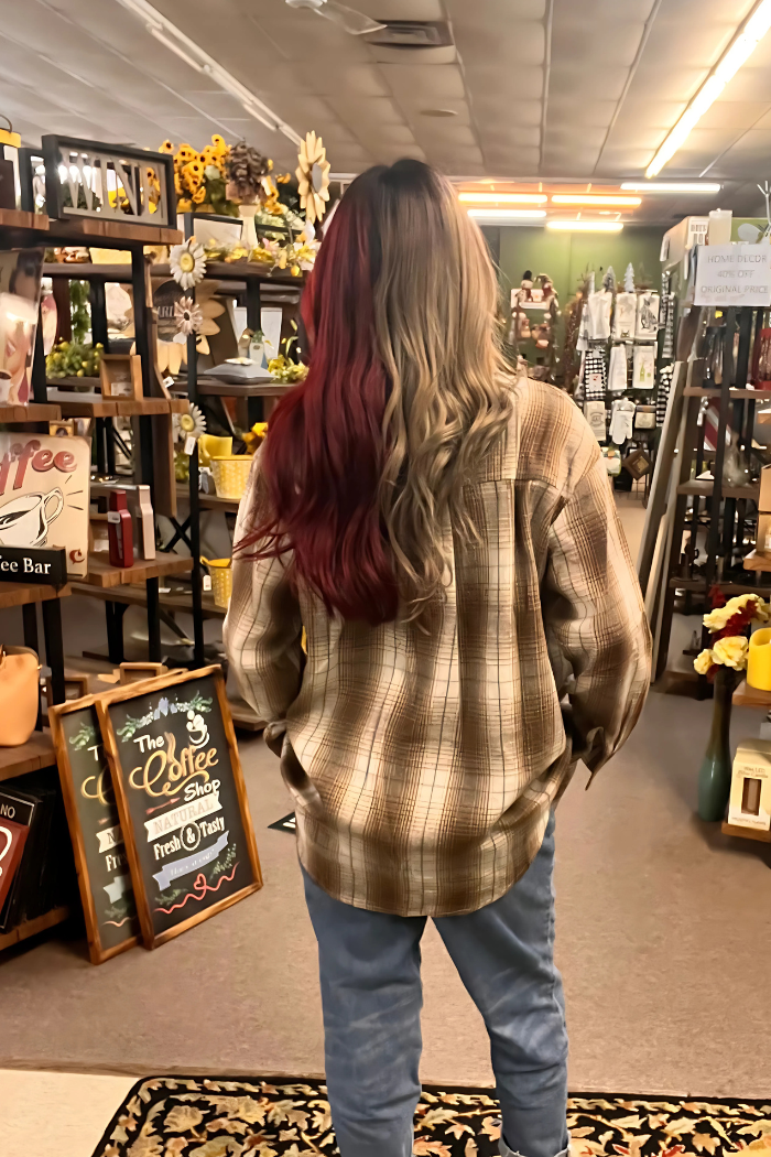 An image captured from the back shows a person wearing a brown and cream plaid flannel shirt and blue jeans, standing in the aisle of what appears to be a cozy, rustic-style shop.