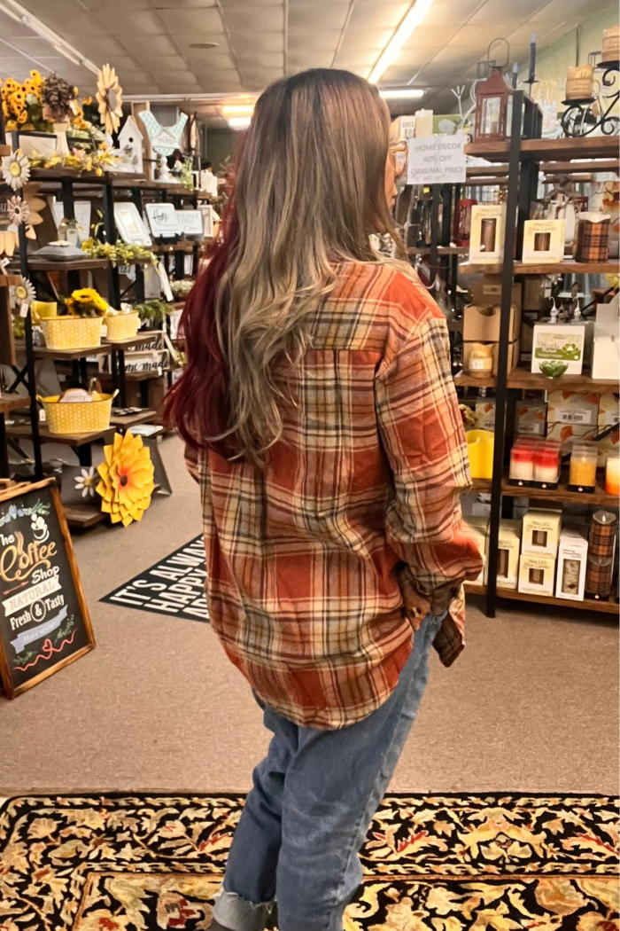 Back view of a woman wearing a rust-colored plaid flannel shirt.