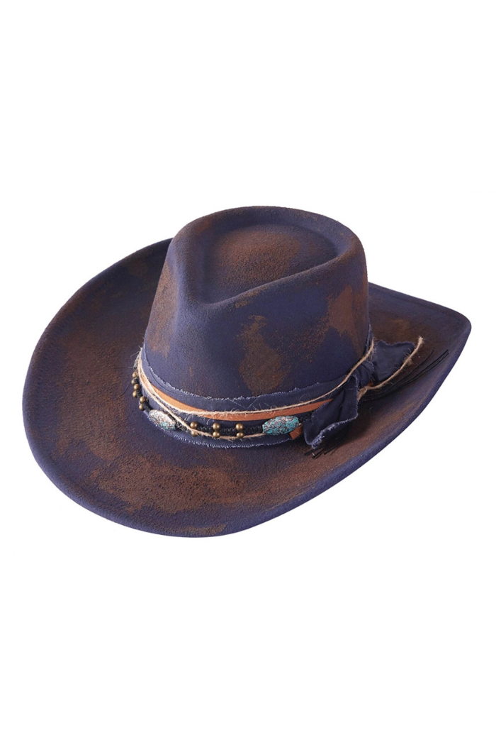 A distressed, rustic blue cowgirl fedora hat with brown accents, featuring a decorative band adorned with beads and fabric details.