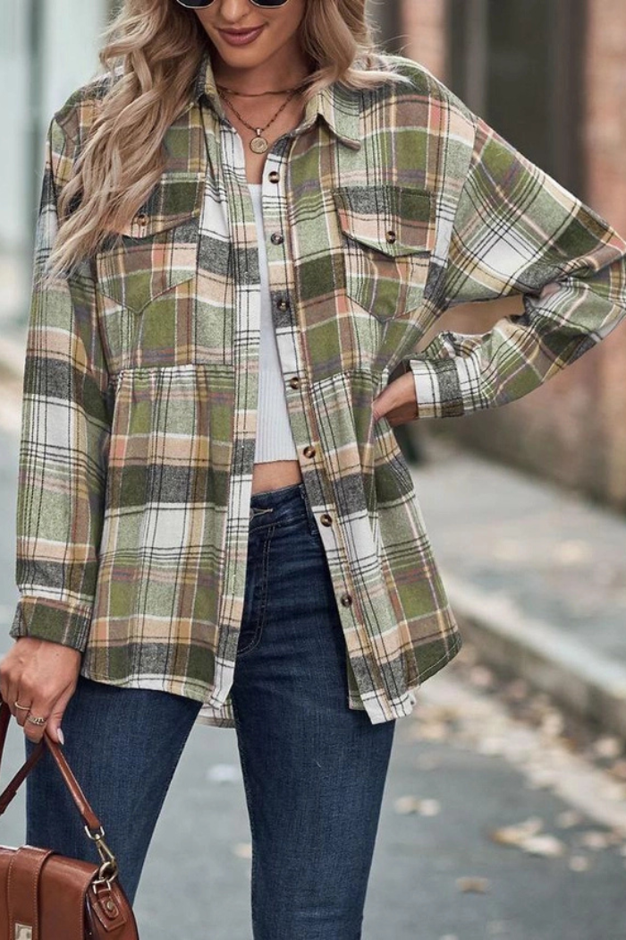 A woman wearing a green, white, and tan plaid flannel shirt over a white top, paired with blue jeans, and holding a brown handbag.