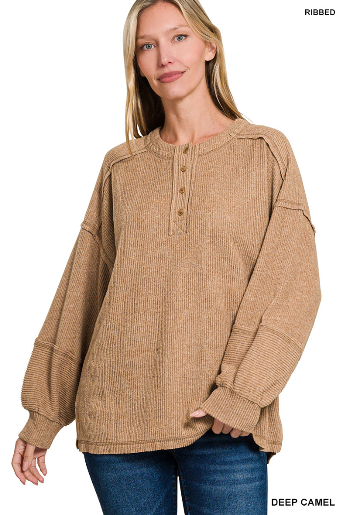Wearing a Brushed Ribbed Henley Top in deep camel with a relaxed fit, dropped shoulders, and wide sleeves, a woman pairs it with blue jeans and smiles against a white background—perfect for cozy loungewear.