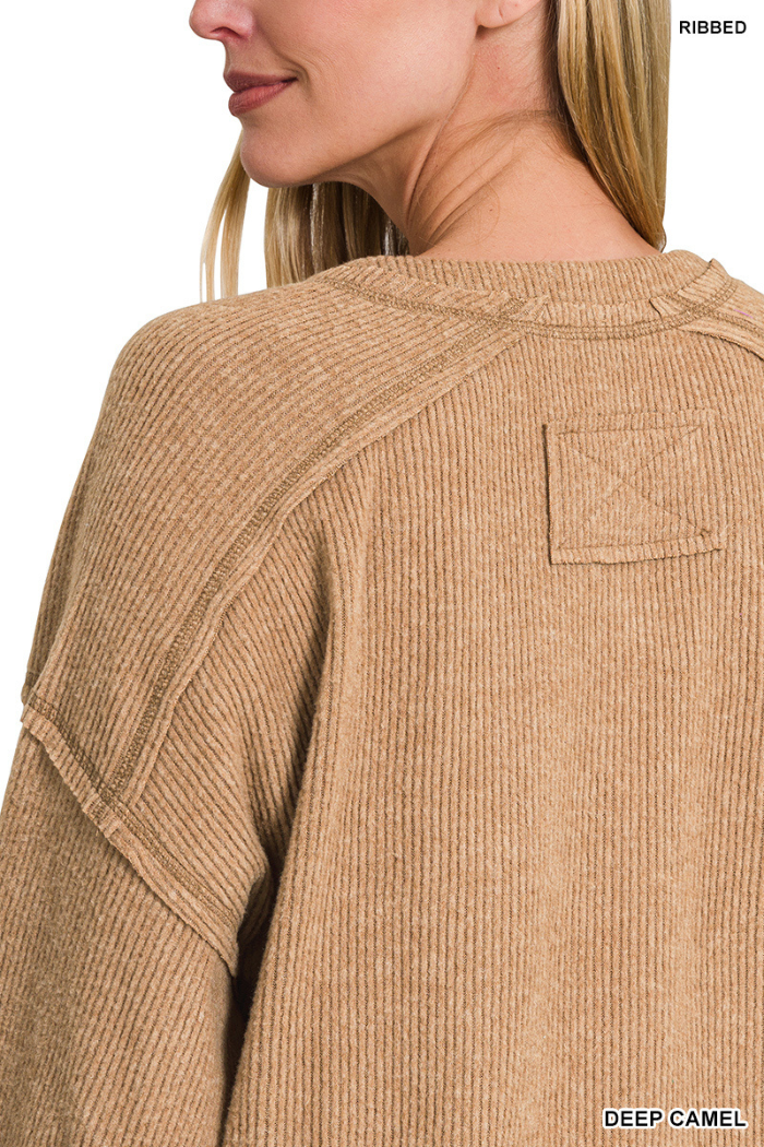 Close-up of a woman wearing the Brushed Ribbed Henley Top in camel. Its relaxed fit and textured knit create cozy loungewear vibes, while a small patch near the neckline adds a stylish detail.