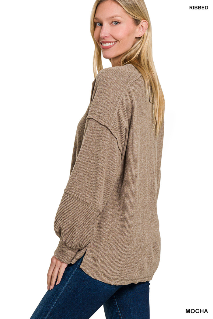 A woman with long blonde hair smiles in a relaxed fit, mocha Brushed Ribbed Henley Top with balloon sleeves and blue jeans, posing three-quarters against a white background.