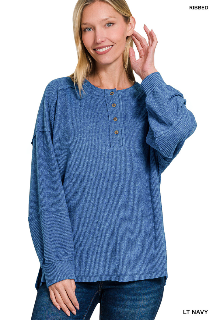 A smiling woman wears the Brushed Ribbed Henley Top with buttons at the collar and blue jeans, standing against a white background.