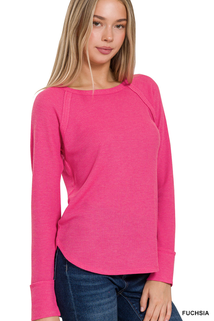 A woman with long blonde hair models the Waffle Knit Long Sleeve Top in bright fuchsia, featuring a round neckline and slightly curved hem, paired with dark blue jeans against a white background.