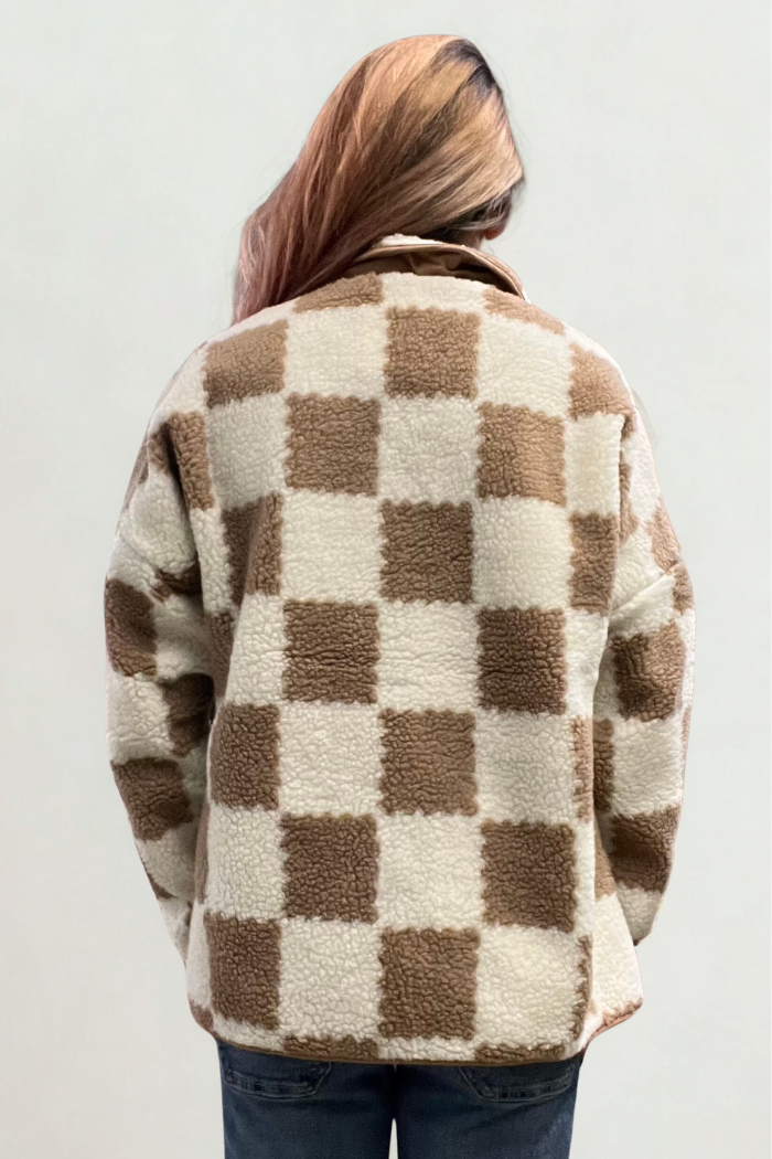 A woman is shown from behind, wearing a brown and cream checkered fleece jacket.