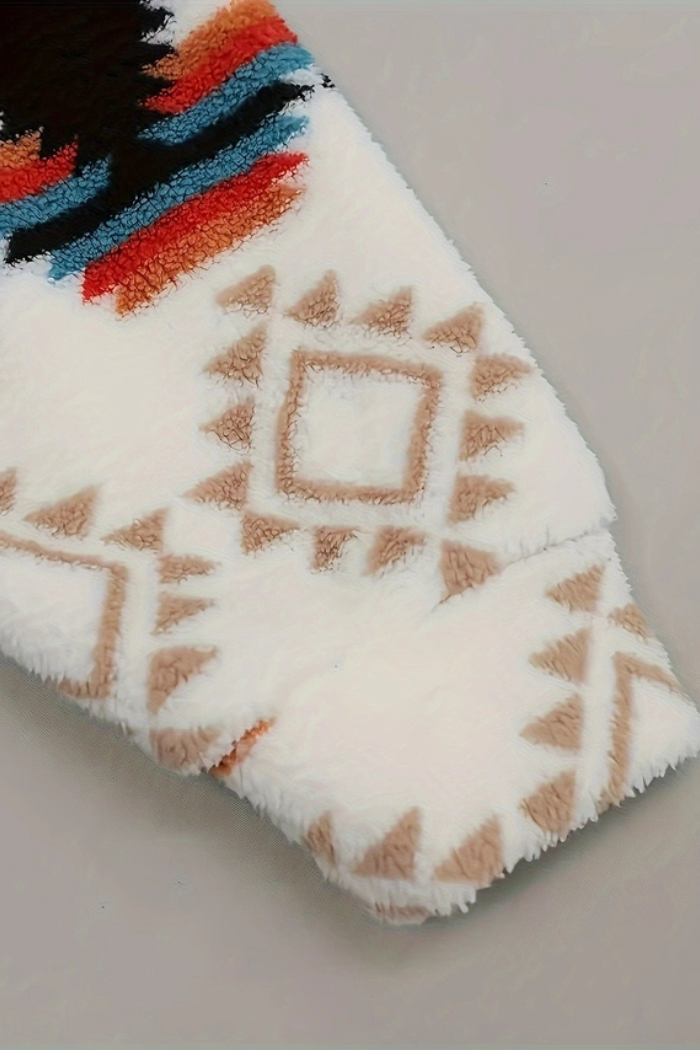 A close-up shot of a white sherpa shacket featuring a geometric pattern. The sleeve has a repeating pattern of tan-colored triangles and squares, while the torso area (visible on the left) has a colorful striped pattern in black, orange, and blue. The texture of the shacket is soft and fuzzy. 