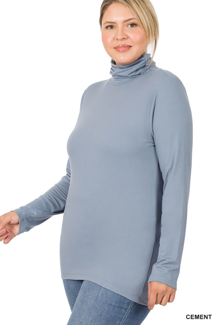 A woman smiles with her hair pulled back, wearing the Plus Premium Microfiber Mock Neck Top in light gray and blue jeans.