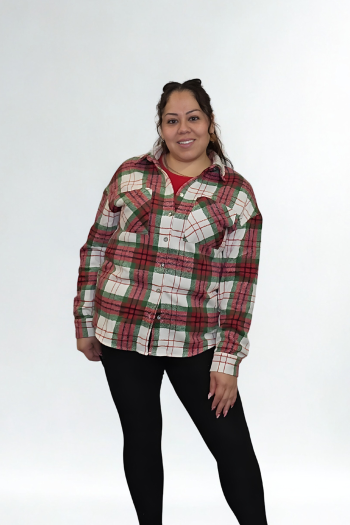 A smiling woman poses against a white background, wearing the Christmas Plaid Flannel Shacket over a red top and black leggings. Her hair is tied back and her hands are at her sides.