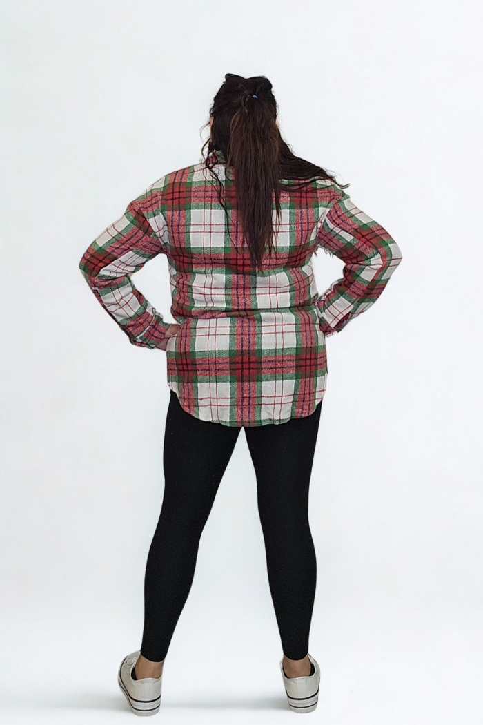 A person with long brown hair stands with hands on hips, wearing the Christmas Plaid Flannel Shacket, black leggings, and white sneakers against a plain white background.