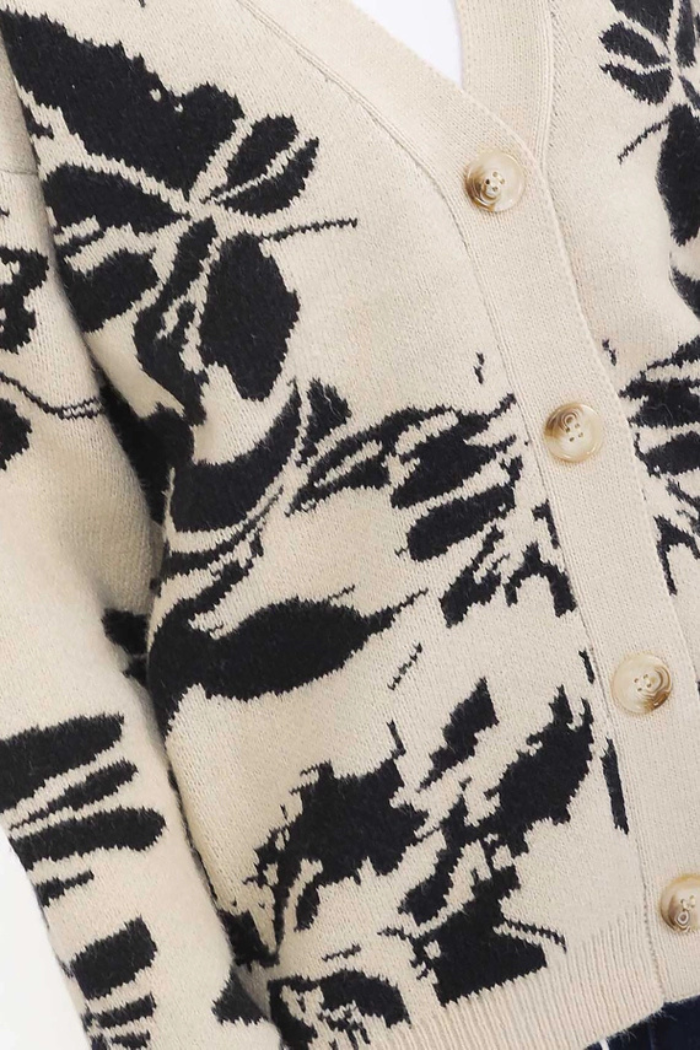 A close-up of the Multi Print Button Cardigan—an oversized beige knit featuring a black abstract floral pattern and light buttons down the front, perfect for cozy winter wear.