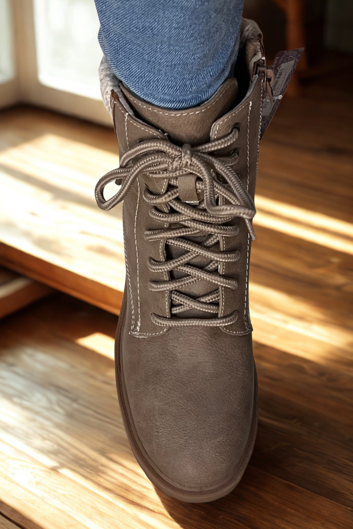 A close-up of a person wearing blue jeans and Sky Solange Wedge Boots, standing on a wooden floor with sunlight streaming in.