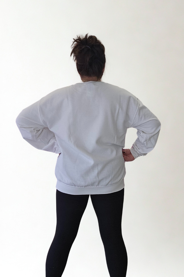 Facing away from the camera with hands on hips, a person models the Lucky Mama Sweatshirt and black leggings against a plain white background.