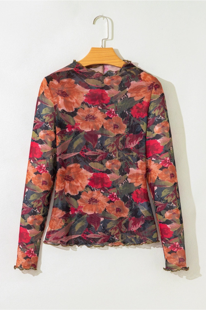 The Floral Mesh Lettuce Top is a long-sleeved, sheer mesh top with lettuce trim and a colorful red, orange, and green floral pattern, shown on a wooden hanger against a plain white wall.