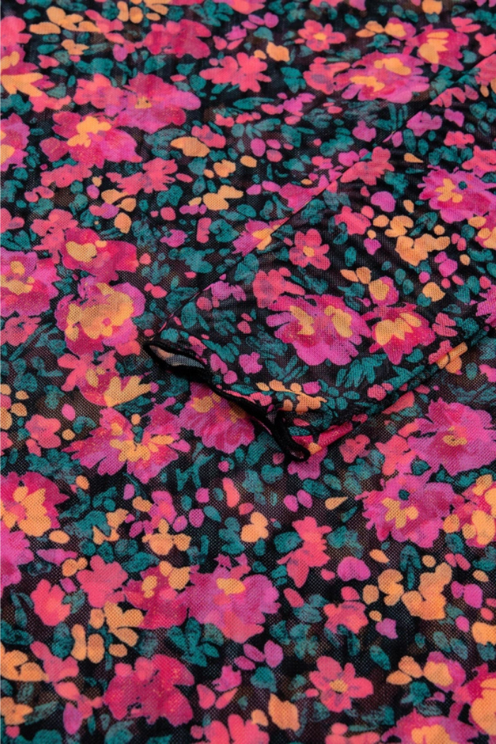 Close-up of the Floral Mock Neck Top shows its colorful pink, orange, and teal floral print on black, plus a center pocket with black trim for a charming vintage-inspired look.