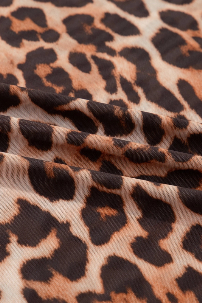 Close-up of the Leopard Mesh Mock Neck Top’s fabric, showcasing its beige background with irregular black and brown leopard print spots and gentle folds.