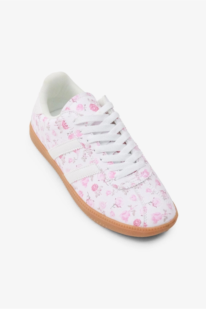 The Floral Lace-Up Sneakers are casual women’s shoes in white vegan leather with pink floral patterns, white laces, and a light brown rubber sole, shown against a plain white background.