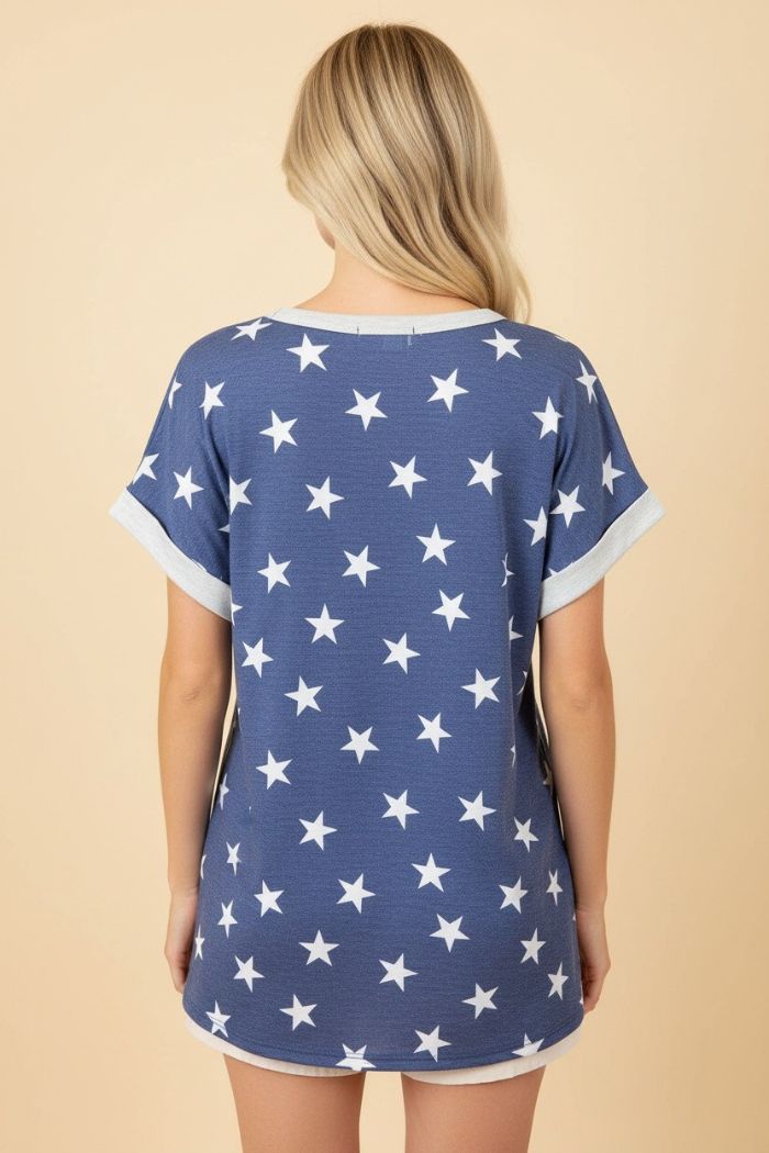 A person with long blonde hair is shown from behind wearing the Plus Star Terry Top, a loose-fitting top featuring white stars and light sleeve trim, standing against a beige background.