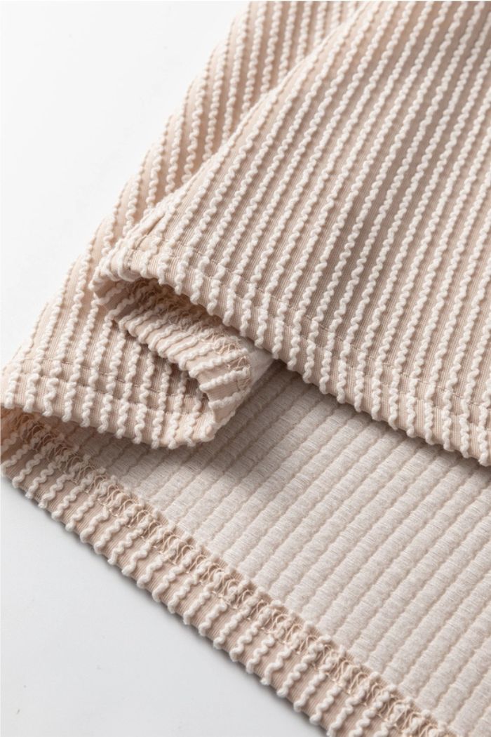 Close-up of the Floral Contrast Ribbed Top in beige, highlighting its textured ribbed pattern, folded edges, and parallel raised lines across the soft knit surface.