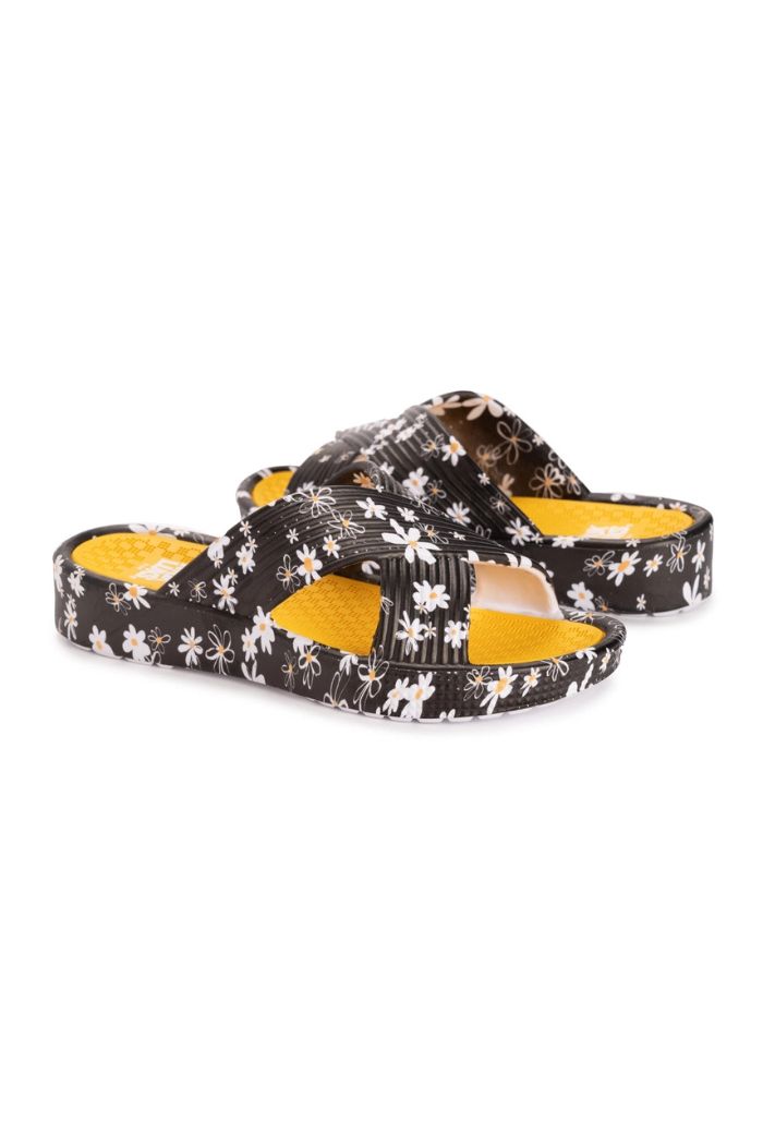 The Black Floral Slip-On Sandals feature an open-toe, crisscross straps, a black base with white floral pattern, and a textured yellow EVA footbed for comfort.