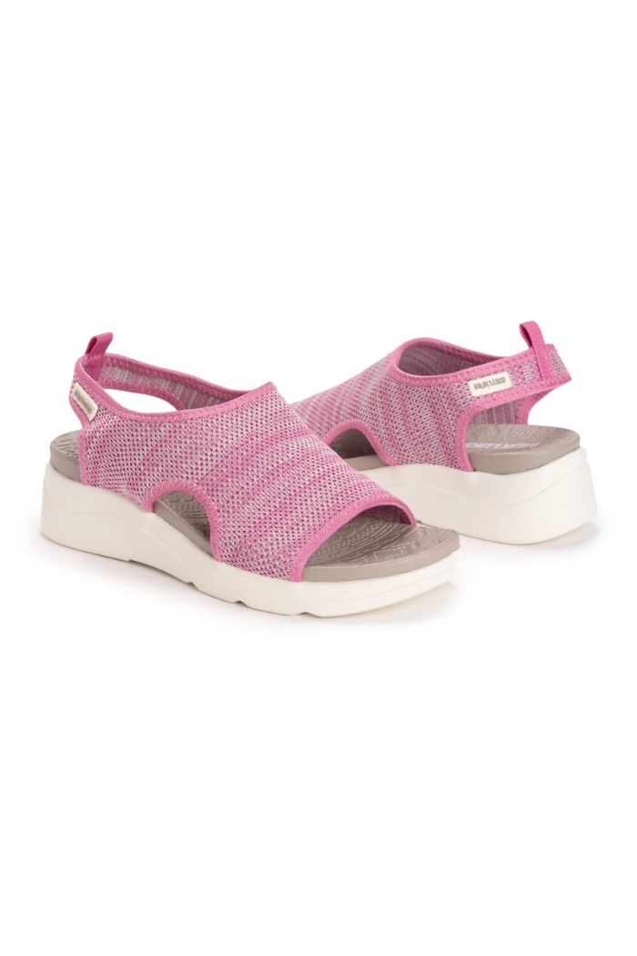 Muk Luks Zahara Sandals in pink feature knit uppers with a mesh design, gray insoles, white soles, and slingback straps for a casual style. Displayed on a white background.