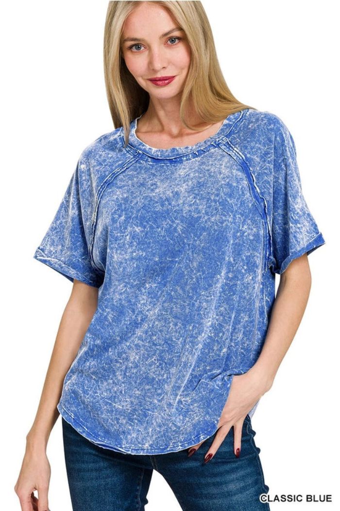 A woman with straight blonde hair wears the Crinkle Washed Raglan Tee—loose-fitting, short-sleeve, and perfect for casual looks with jeans—as she smiles at the camera, one hand in her pocket.