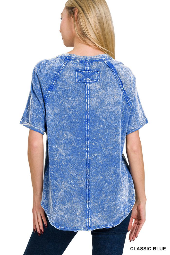 A woman with long blonde hair is shown from the back wearing the Crinkle Washed Raglan Tee, featuring short sleeves, visible seams, and a curved hem. This women's casual tee is displayed against a white background.
