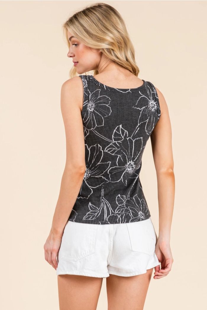 A woman with blonde hair wears the Bombom Floral Ribbed Tank Top and white shorts, standing against a plain beige background—a stylish choice for summer layering.